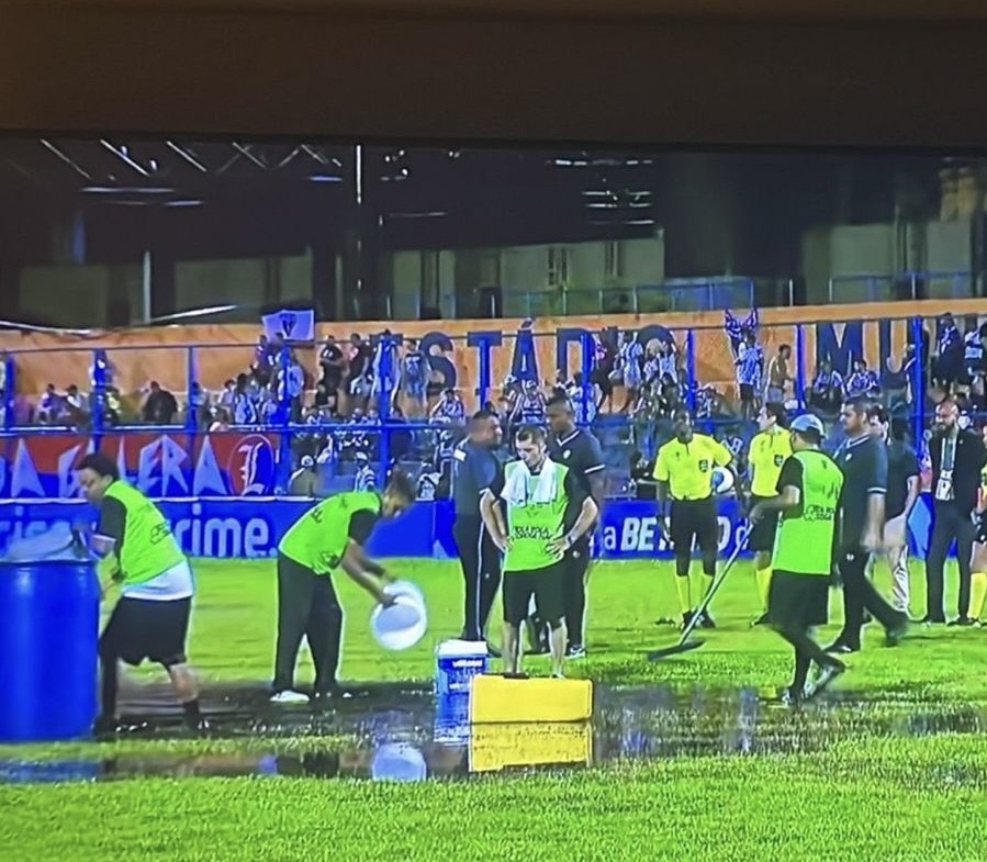 As pessoas tentam “secar” o estádio usando pequenos baldes para retirar a água empoçada