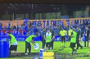 As pessoas tentam “secar” o estádio usando pequenos baldes para retirar a água empoçada (Foto: Reprodução)