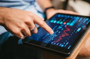 Homem a verificar dados do mercado de ações no tablet (Foto: Freepik)