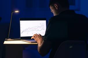 Homem negociando browsing online investimentos de ações à noite (Foto: Freepik)