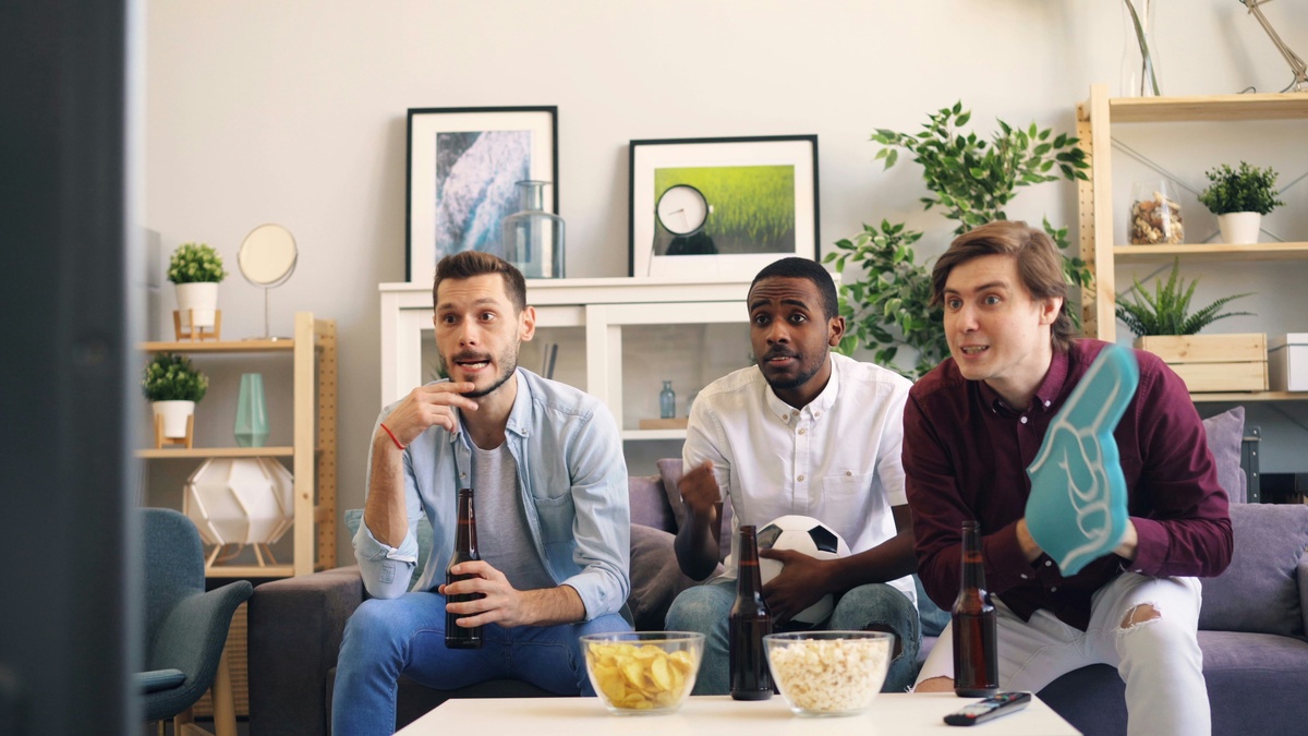 Três homens sentados em um sofá em uma sala de estar