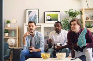Três homens sentados em um sofá em uma sala de estar (Foto: Unsplash)