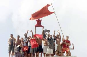 Brasil, Rio de Janeiro, RJ, 19/04/2002 Rebelião de presos na Casa de Custódia Jorge Sant'ana, em Bangu. Presos no telhado fazendo agito com a bandeira da facção Comando Vermelho (CV). - Crédito:CARLOS MORAES/AGÊNCIA O DIA/AE/Código imagem:155582 (Foto: Divulgação / InfoMoney)